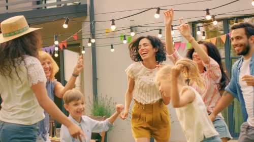 Glad familj och vänner som dansar tillsammans i trädgården